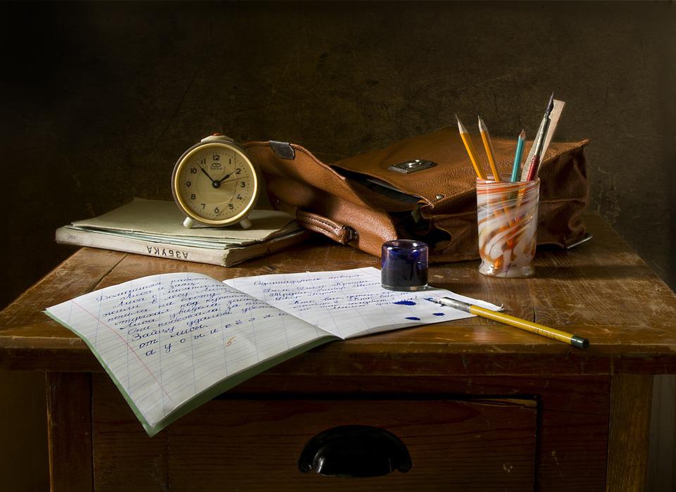 School supplies spilled onto an old wooden desk.